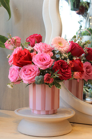 Pink and red rose flower arrangement in a striped vase